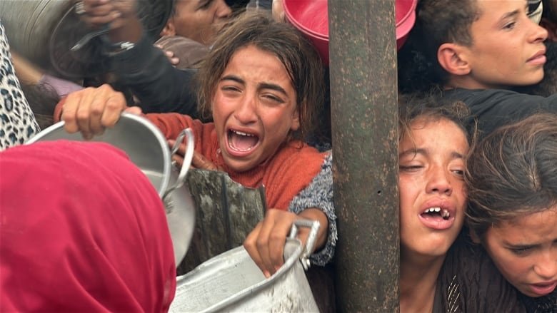 Children with pots in hand reach out for food.