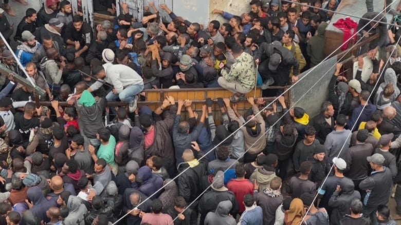 People trying to jump a fence to get into a bakery.