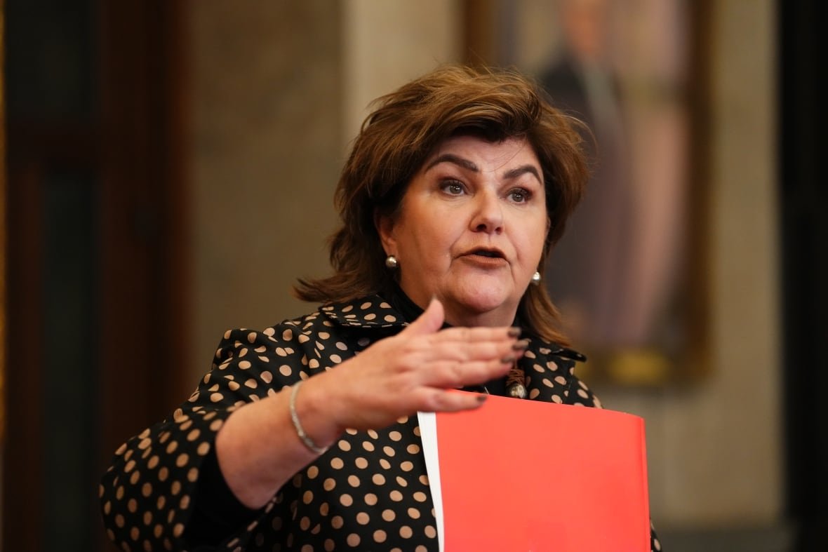 A woman stands at a podium in a hallway.