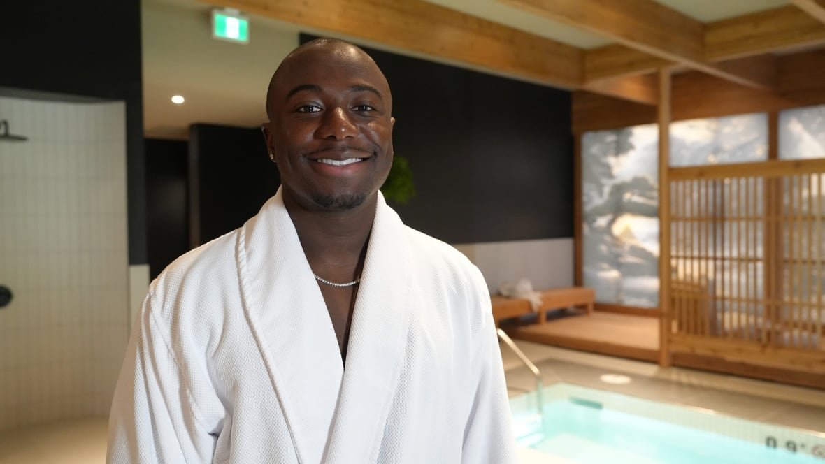 albert-banahene-1 A man wearing a white robe poses for a photo in front of a pool.