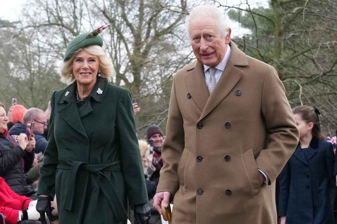 britain-royals-christmas-1 A woman in a green coat and hat and a man in a tan-coloured coat walk side by side.