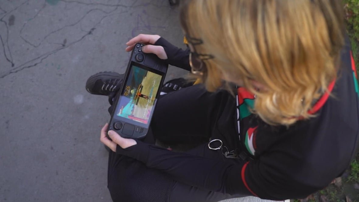 daffodil-street-uni-x-4 A person with blond hair plays a game on a tablet-like gaming device.