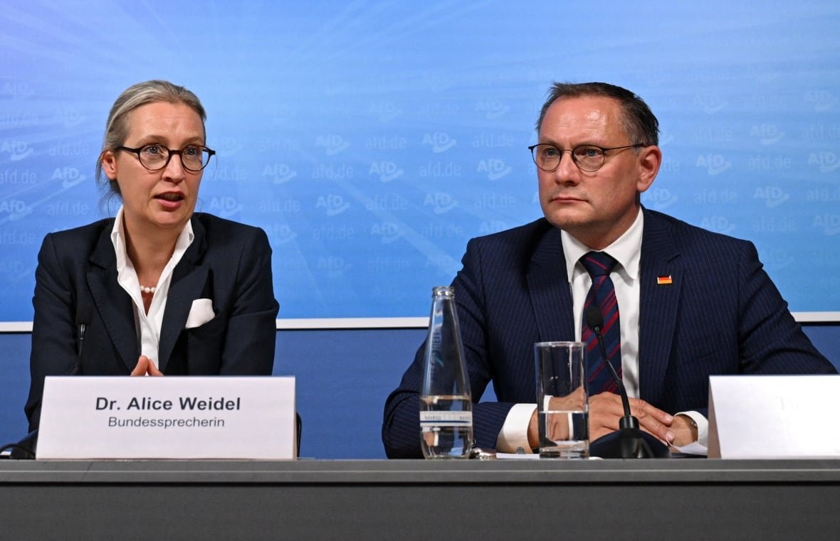 eu-election-germany-reactions A man and a woman sit at a table and speak into microphones.