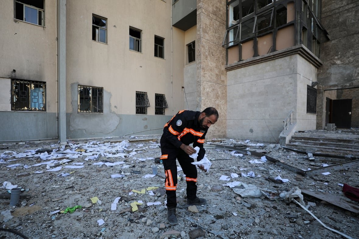 israel-palestinians-gaza-hospital-4 A man looks at papers on the ground at the site of an airstrike.