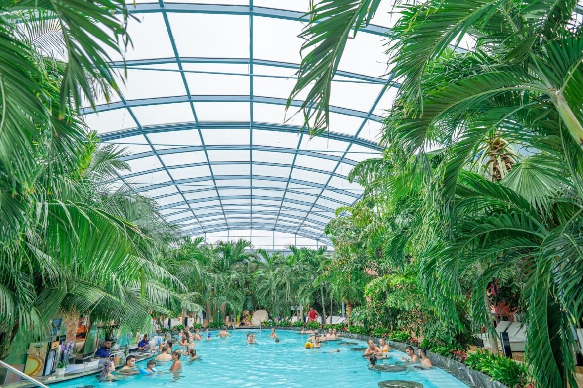 therme-canada This rendering by Therme Canada shows an indoor pool full of people with plants and palm trees lining the circumference.