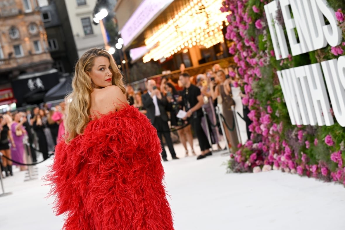 blake-lively-it-ends-with-us-1 A person in a courtyard at a movie premiere looks back toward the camera.