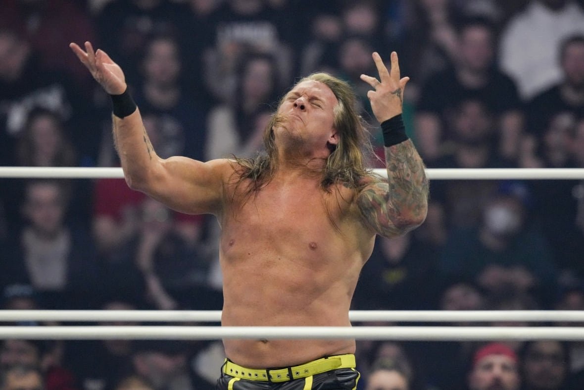 wre-aew-dynamite-20240320-1 A wrestler with long hair gestures in the ring with his arms in front of his body