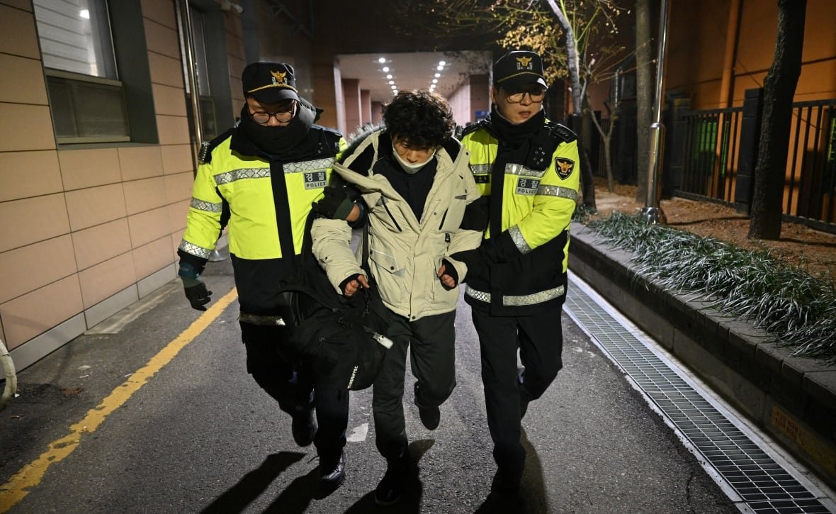 2193894817-1 Police officers detain a person.
