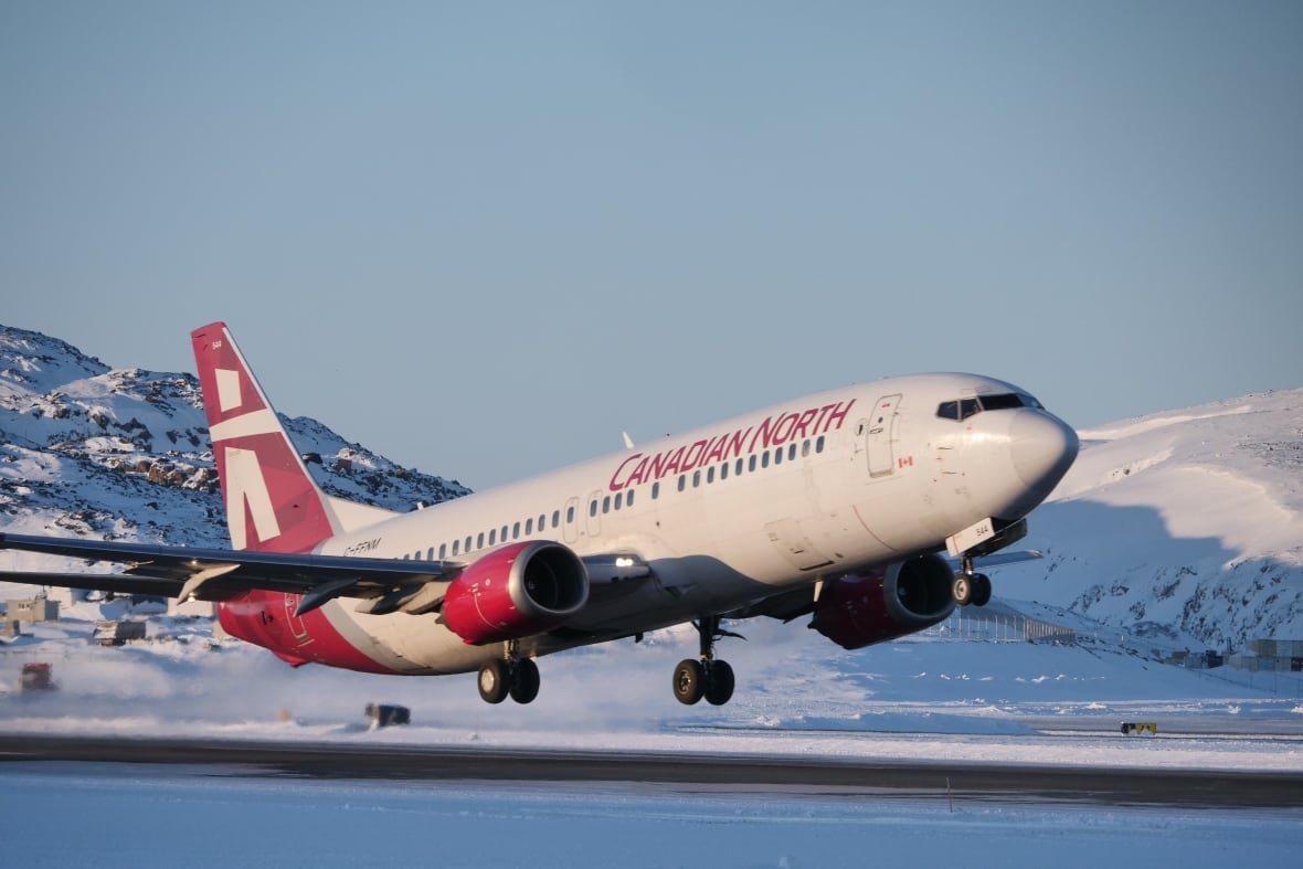 canadian-north A Boeing jet with white and red livery takes off from a snowy Northern airport on a cloudless, sunny day.