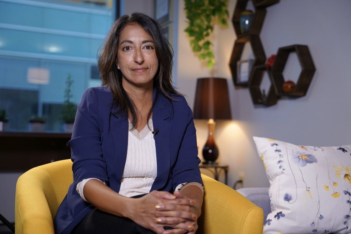 dr-sabina-abidi woman sitting in a yellow chair wearing a blue blazer looks into the camera