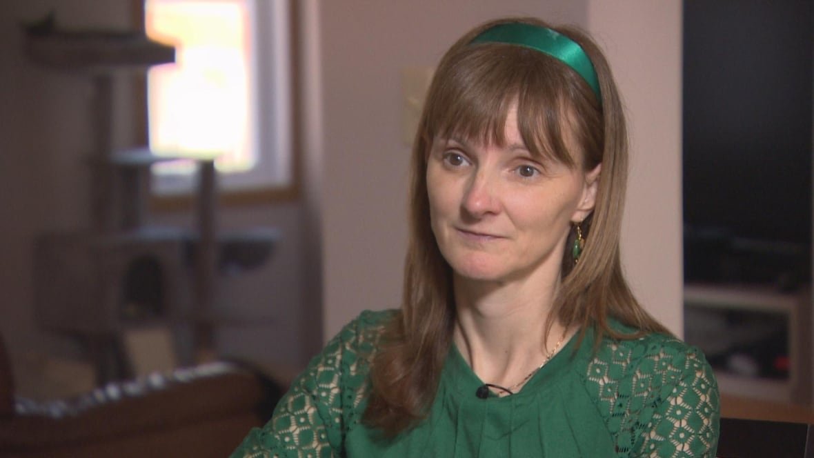 julie-lajoie-1 A woman in a green shirt and green headband is seated in a room.