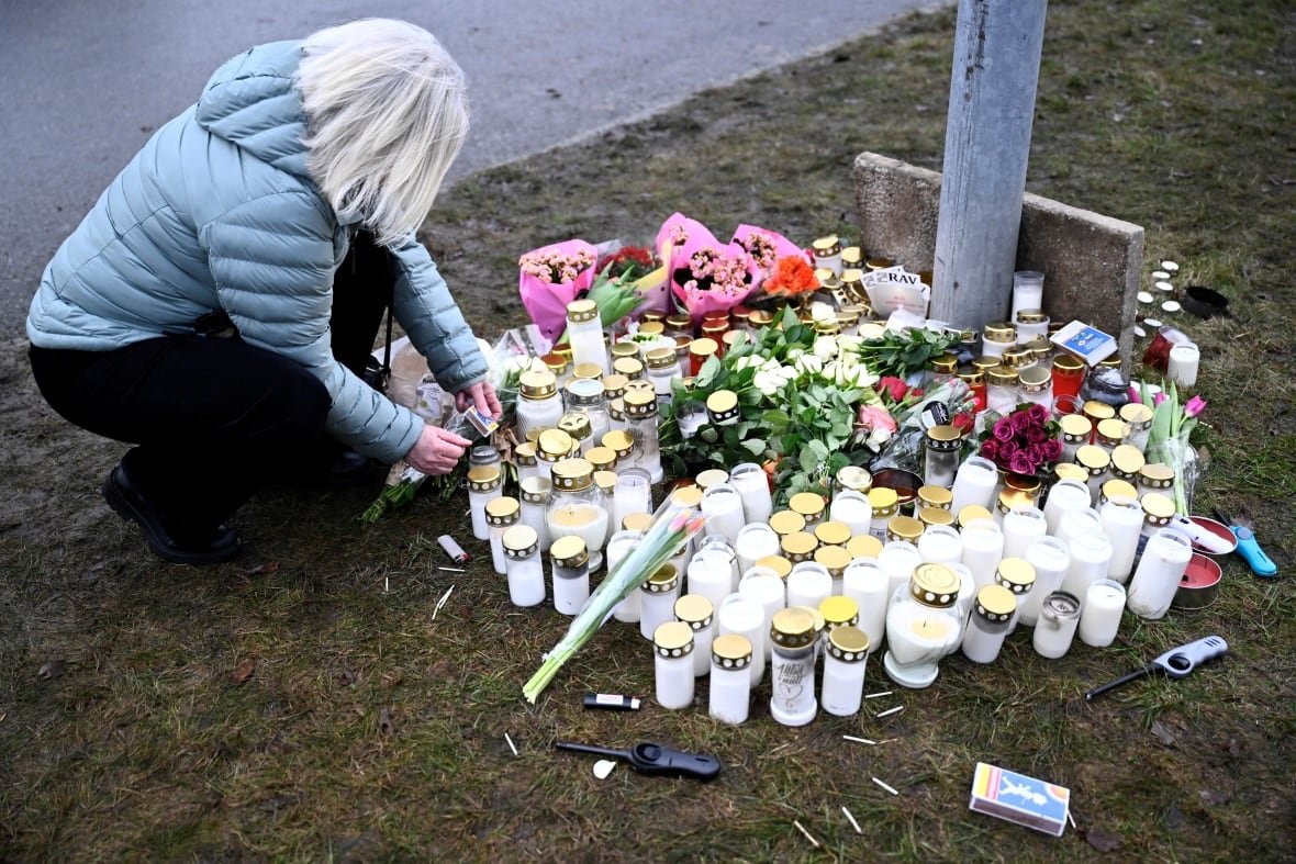 sweden-crime-4 A person crouches to light a candle at a makeshift vigil.