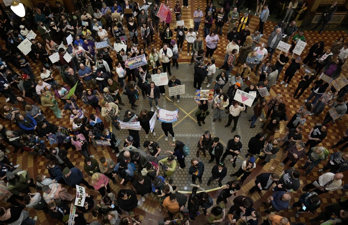 transgender-civil-rights-1 A photo from above shows a huge crowd of people standing in a wide room, with many of them holding signs.