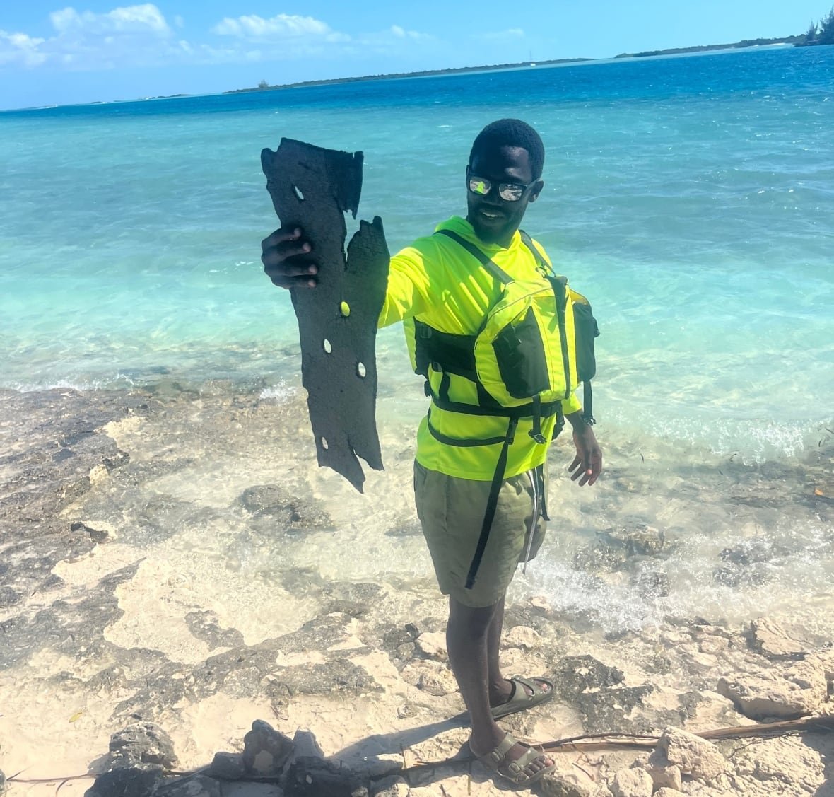 turks-caicos-starship-debris-1 A person holds up debris as they stand next to a body of water.