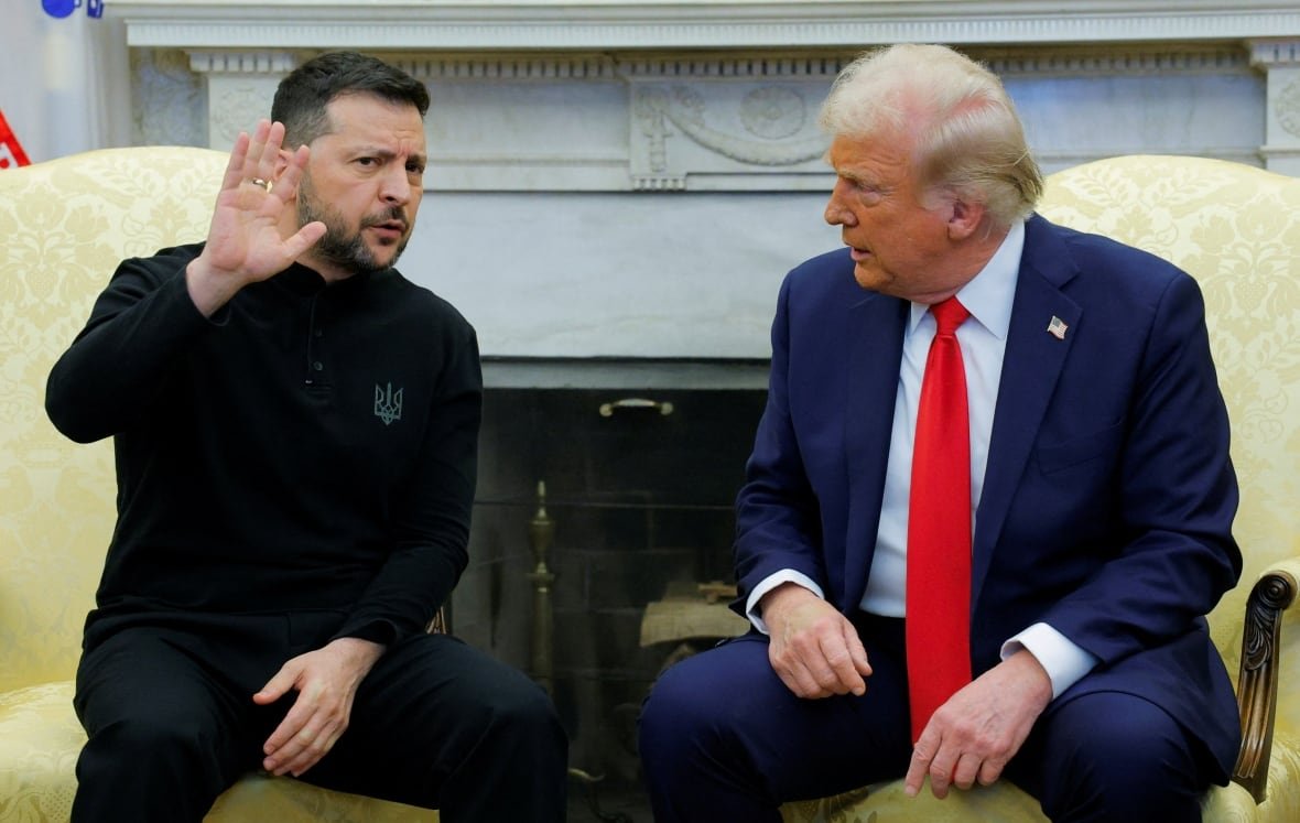 ukraine-crisis-usa-1 A man in a black suit raises his hand as another man in a blue suit looks at him in anger.