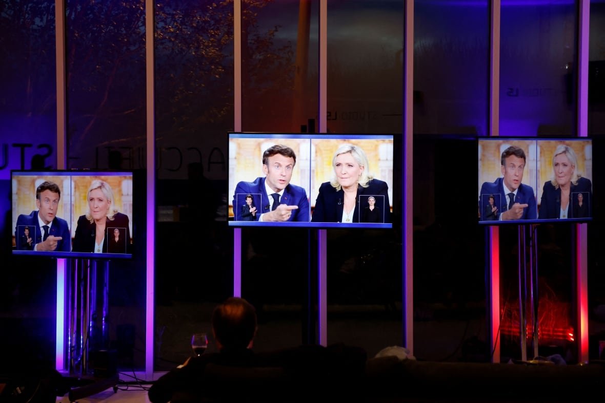 1240112926 Television screens are shown, bearing a split screen image of a cleanshaven brown-haired man, and a woman with blonde hair.