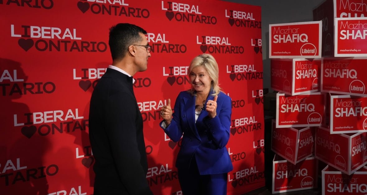elxn-ont-20250206-2 Bonnie Crombie gestures two thumbs up as she stands in front of a backdrop with the words 'Liberal Ontario' repeated many times.