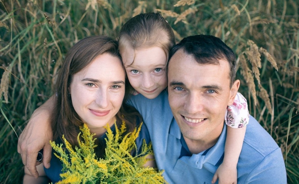 olena-riznyk-family A family smiles at the camera.