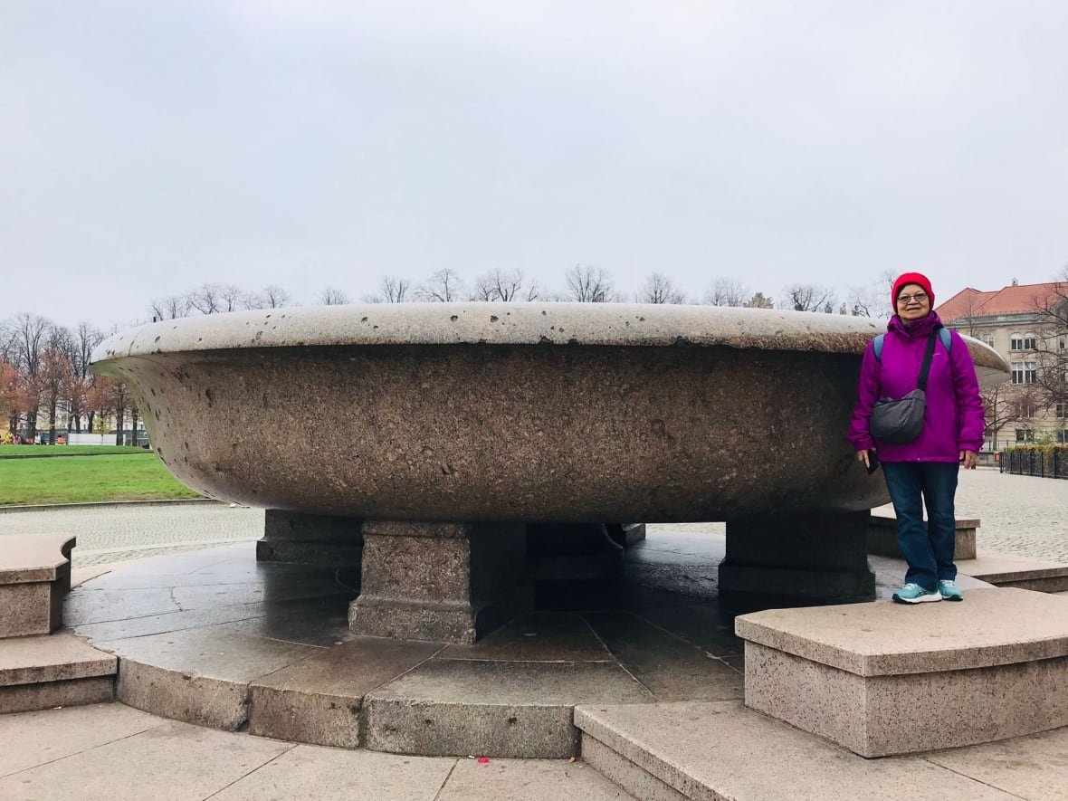 siok-har-lim-1 Woman in fuchsia jacket standing beside monument, smiling.