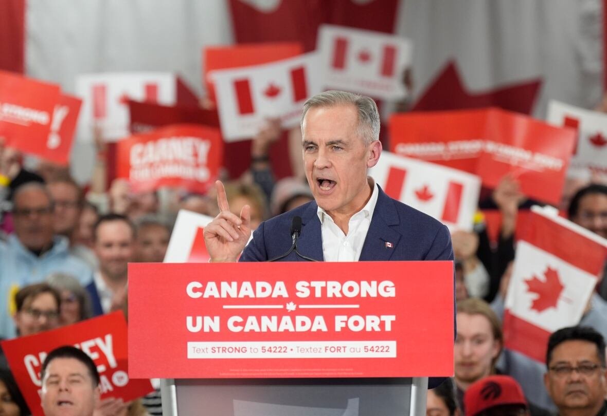 fedelxn-liberals-20250401-1 A man stands at a podium with the words "Canada Strong" and dozens of people holding signs with Canadian flags behind him.
