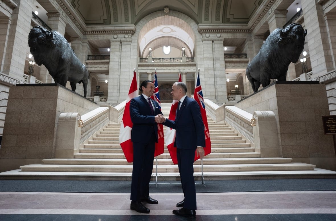 fedelxn-liberals-20250401 Two men shake hands in front of flags in a legislature lobby.