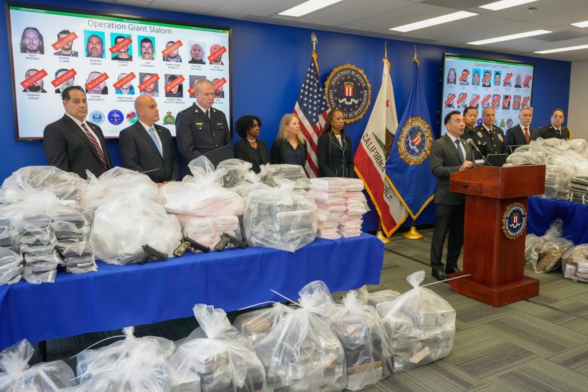 former-snowboarder-drug-trafficking Police officers stand near clear bags full of drugs and other evidence