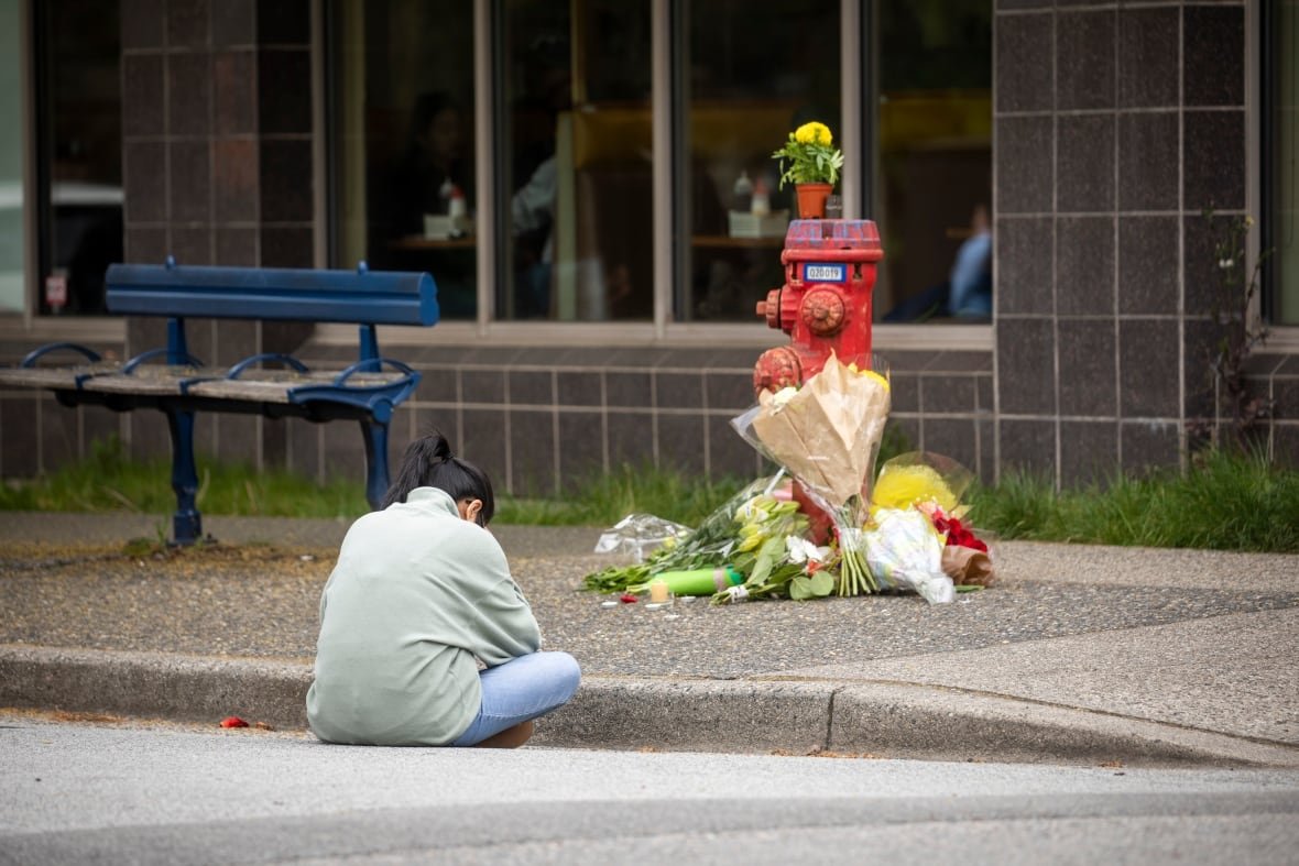 lapu-lapu-police A woman bows her head at a stack of bouquets on a fire hydrant.