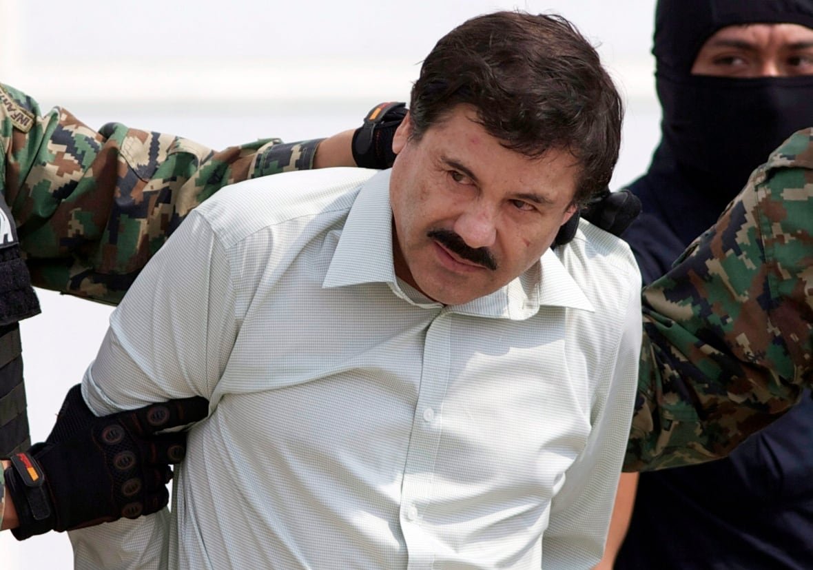 mexico-violence-2 A man in a light shirt is escorted by soldiers in camouflage