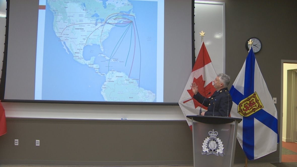 rcmp-operation-harrington A man in RCMP uniform motions to a map of the Americas