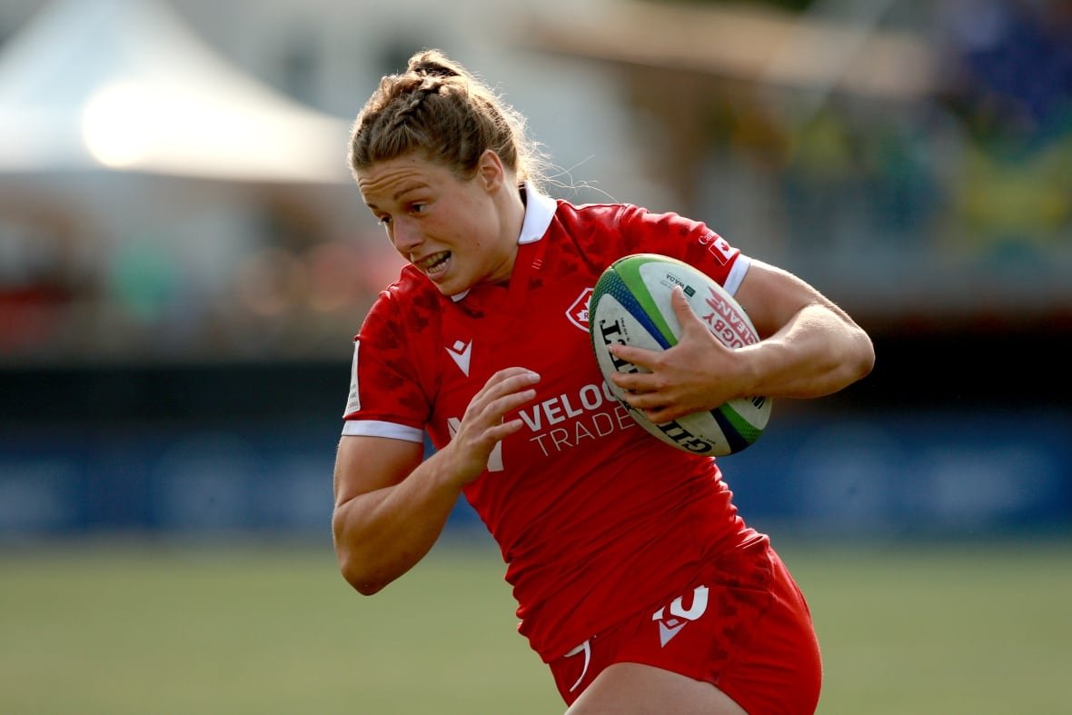 rgu-pacific-four-20240130-1 A woman in a red rugby uniform clutches a ruby ball and runs