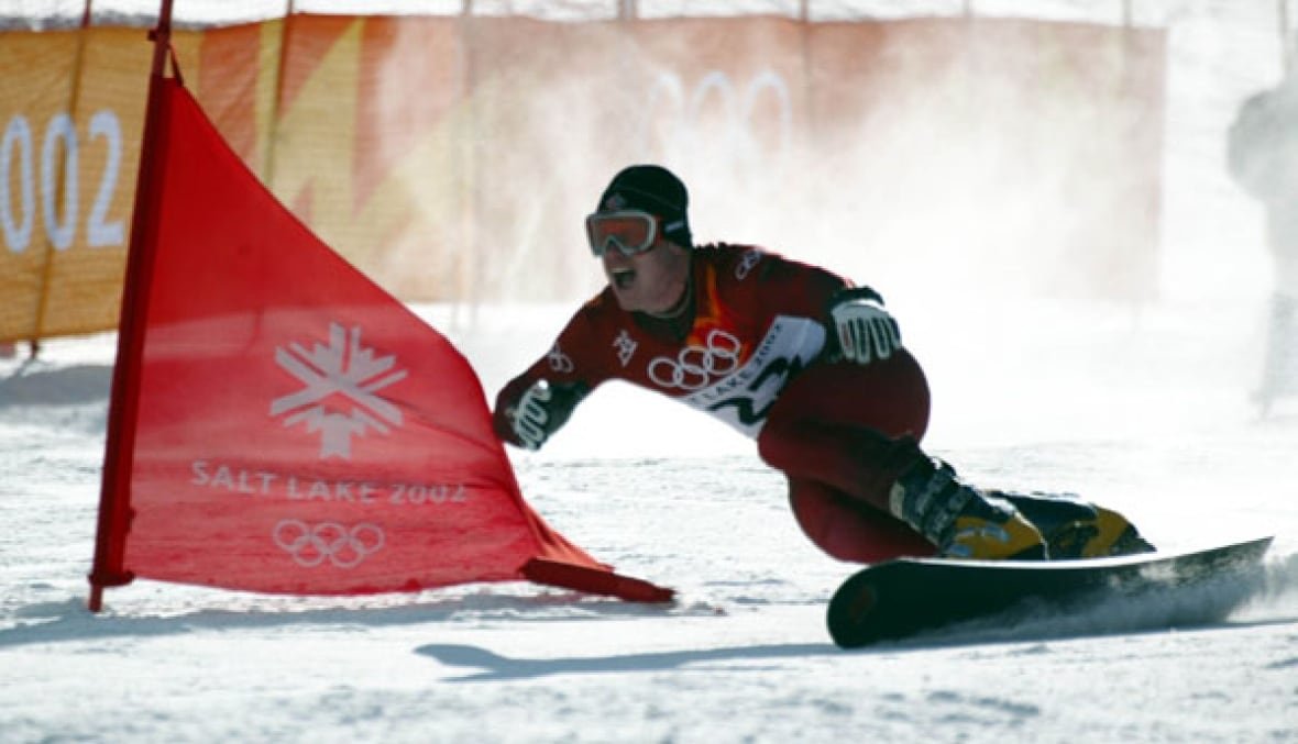 salt-lake-olympics-snowboarding-men-s A snowboarder in red races down a snow-covered hill
