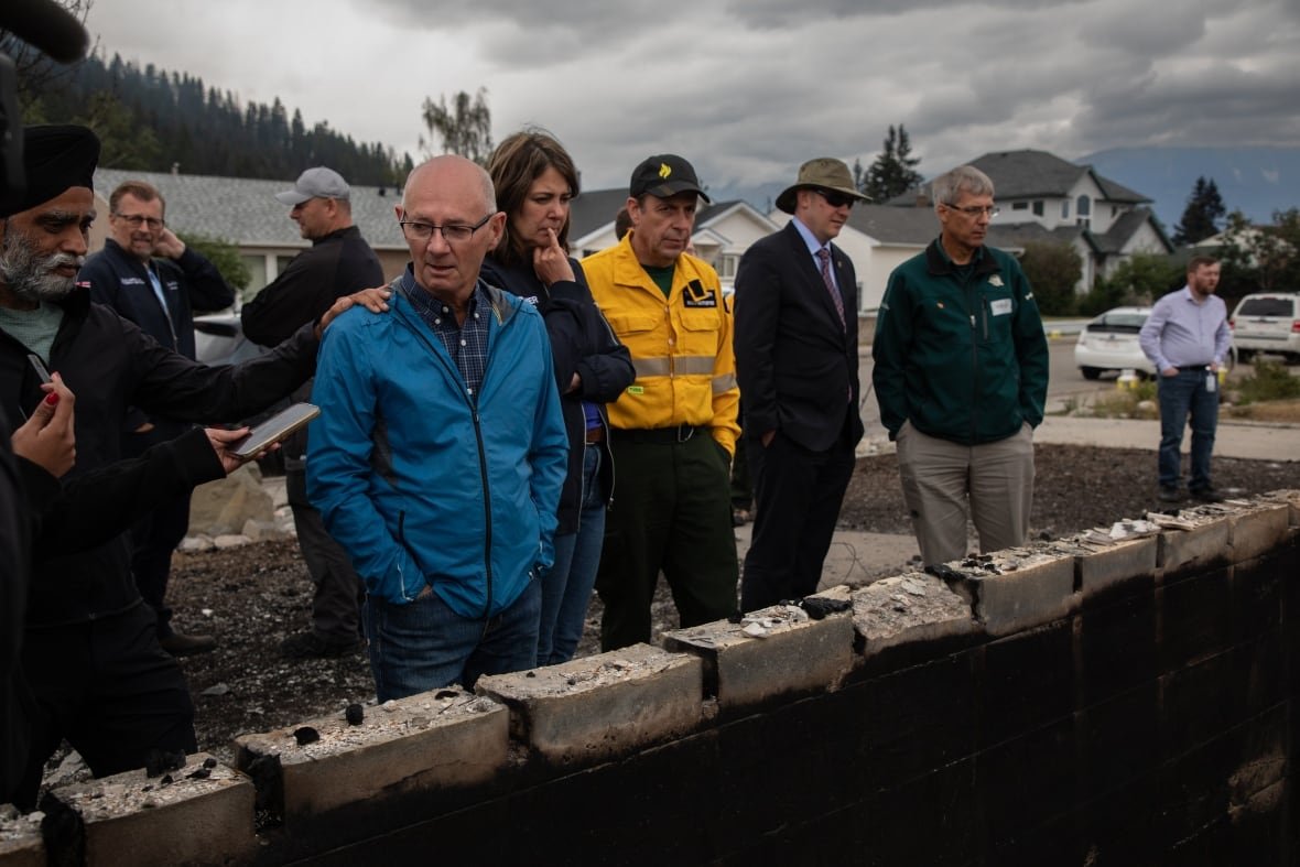 alta-wildfires-2024726-4 A group of people look over the foundation of a burned home.