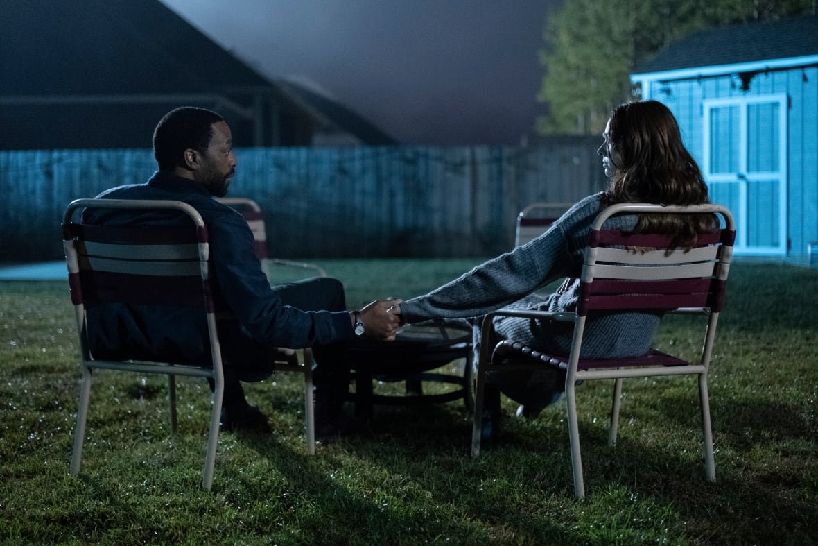 cp174619164-1 A man and woman sit in lawn chairs holding hands and looking at one another.