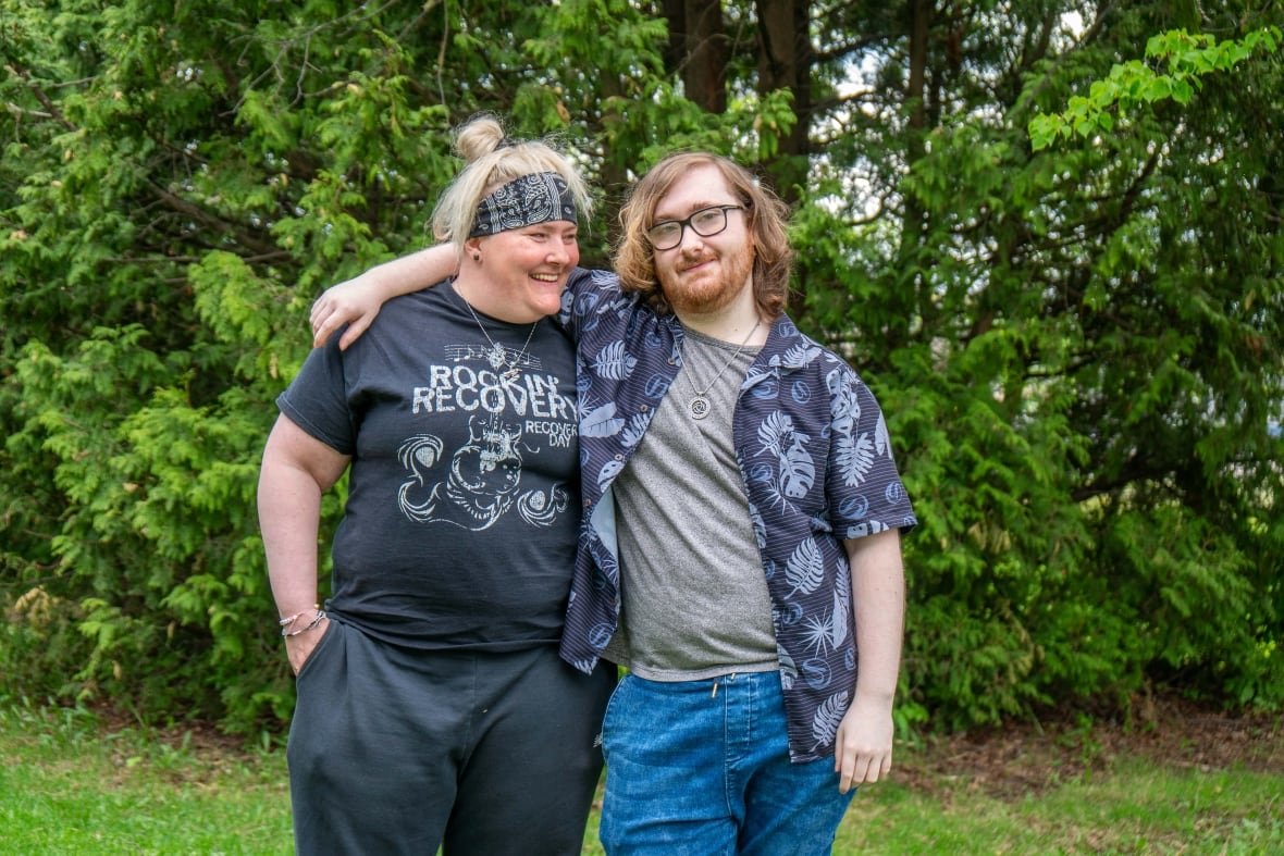 crystal-and-jason-pickering-1 Two people are seen standing outside in a park with their arms wrapped around each other.