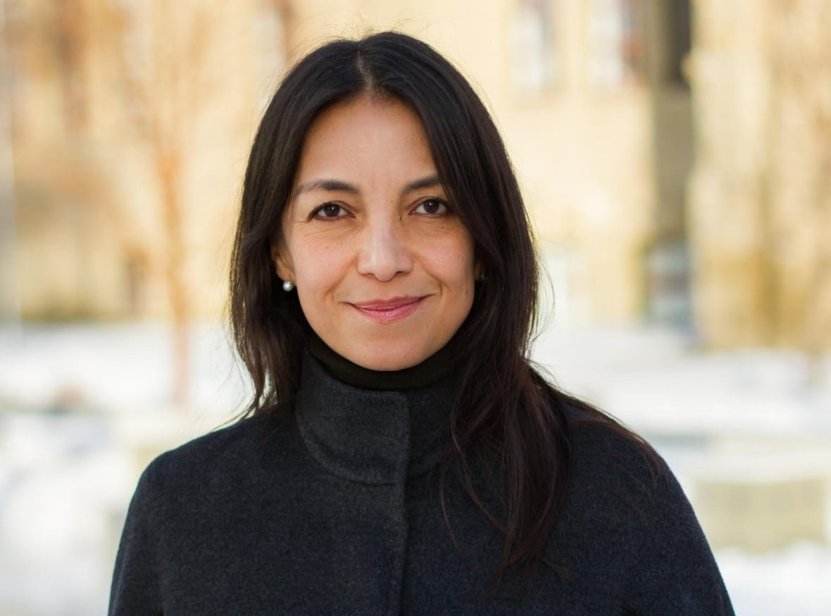 dr-eliana-castillo Castillo is wearing a dark grey jacket and smiling. She's outside and trees and snow can be seen behind her.
