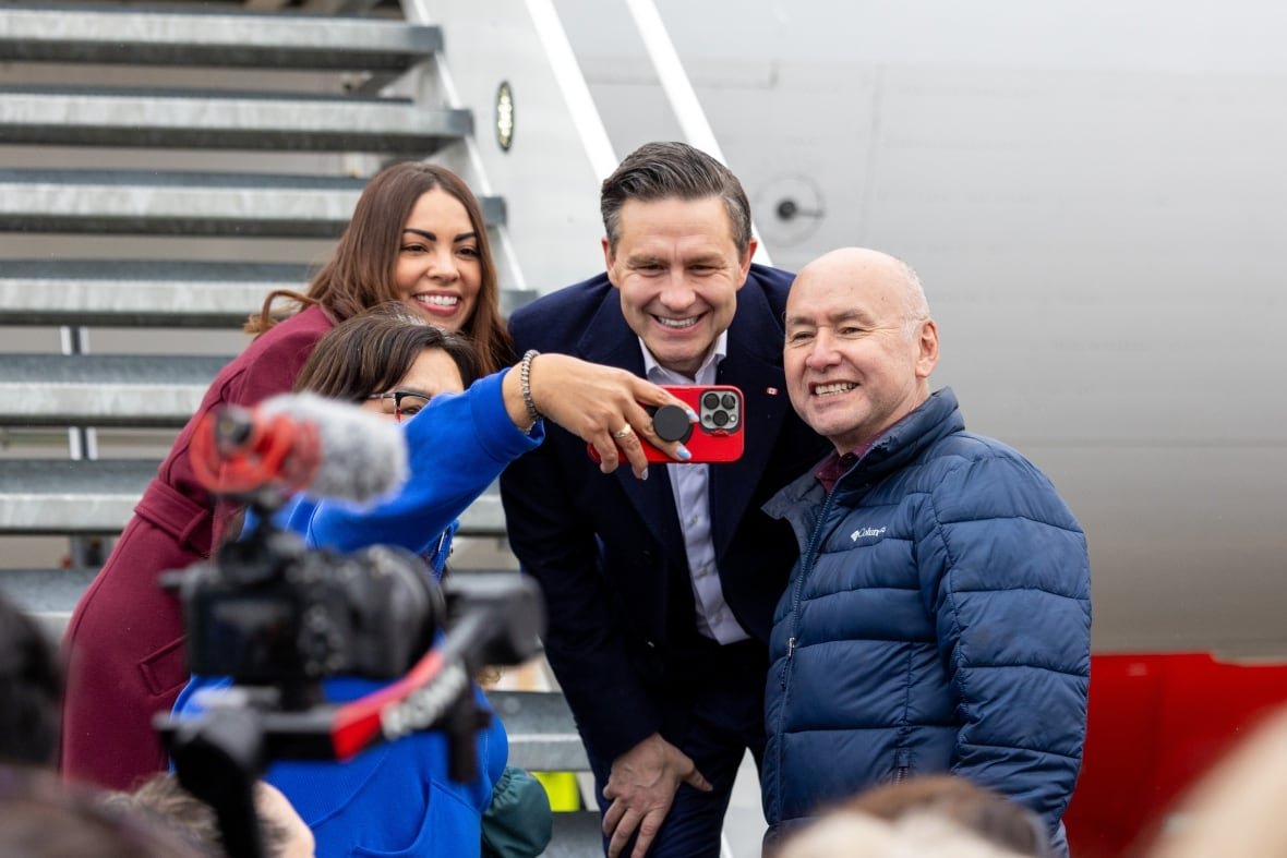 fedelxn-conservatives-20250406-pierre-poilievre-ellis-ross-1 Three people pose for a selfie on the steps of an airplane.