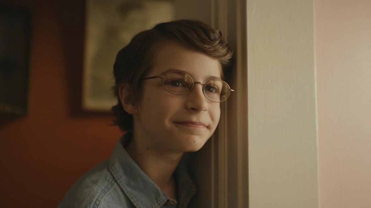 film-review-the-life-of-chuck-4 A smiling young boy leans against a door frame.
