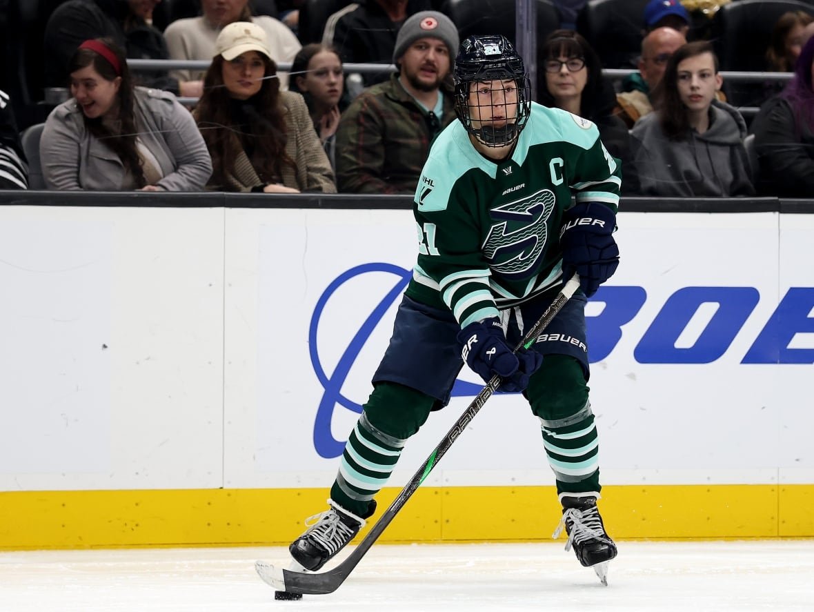 hilary-knight Female hockey player skates on ice with puck.