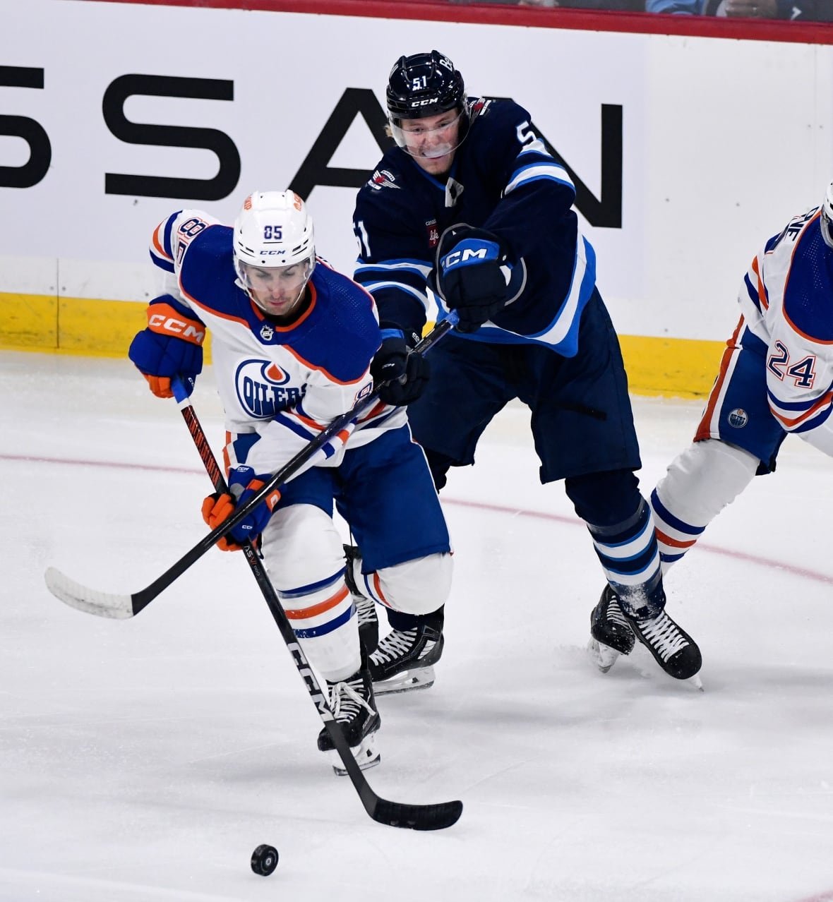 hkn-oilers-jets-20230925-1 A player in blue uses his stick to check a player in white.
