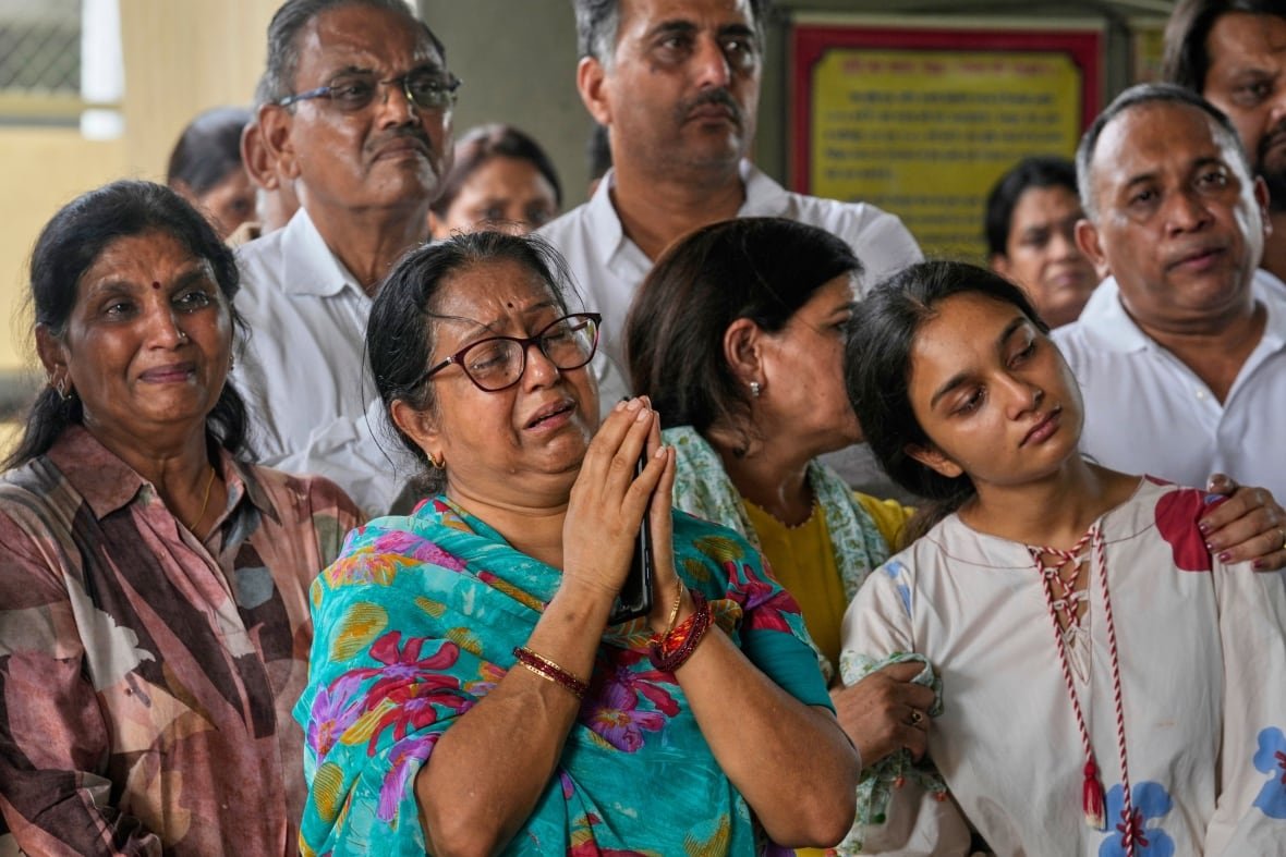 india-plane-crash-5 A group of people clasp their hands together and are crying.