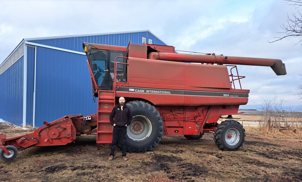 jason-jackson-7 A man stands in front of a large red combine.