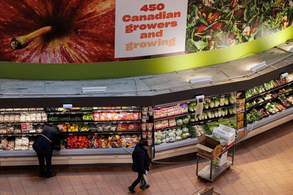 loblaws-buy-canadian-3 Shoppers wander around a grocery store, where a sign above the produce section reads, '450 Canadian Growers and Growing.'