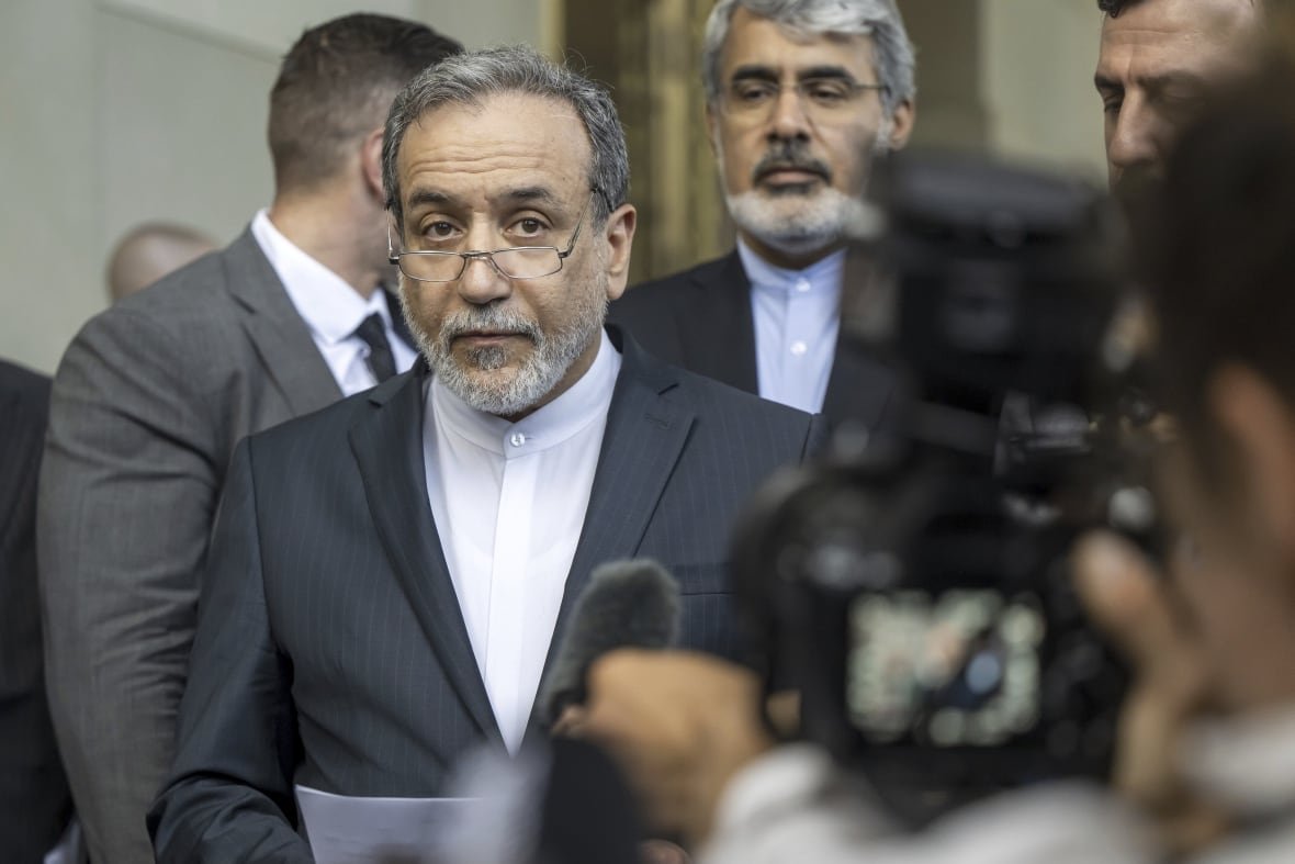 mideast-wars-iran-europe-1 A man in a suit and glasses speaks to reporters.