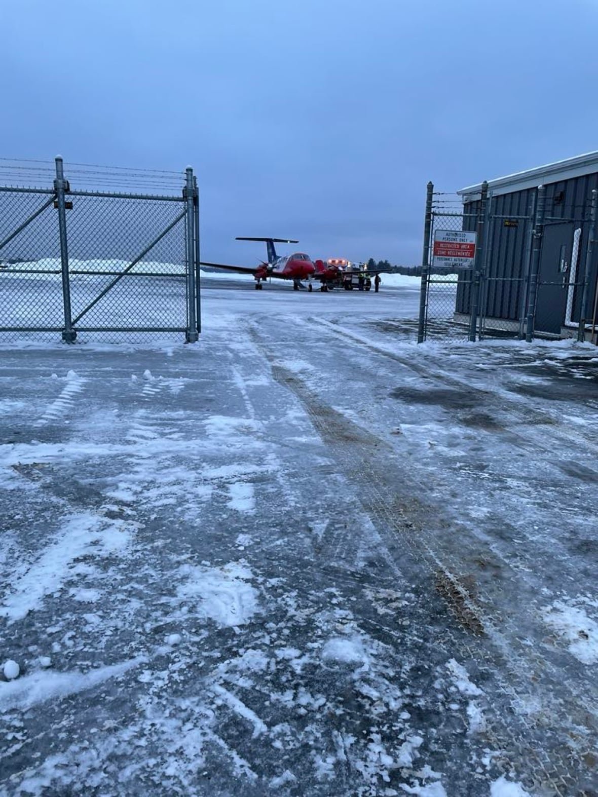 plane-in-new-brunswick-preparing-emergency-airlift A red plane and an ambulance on a snow-covered tarmac.