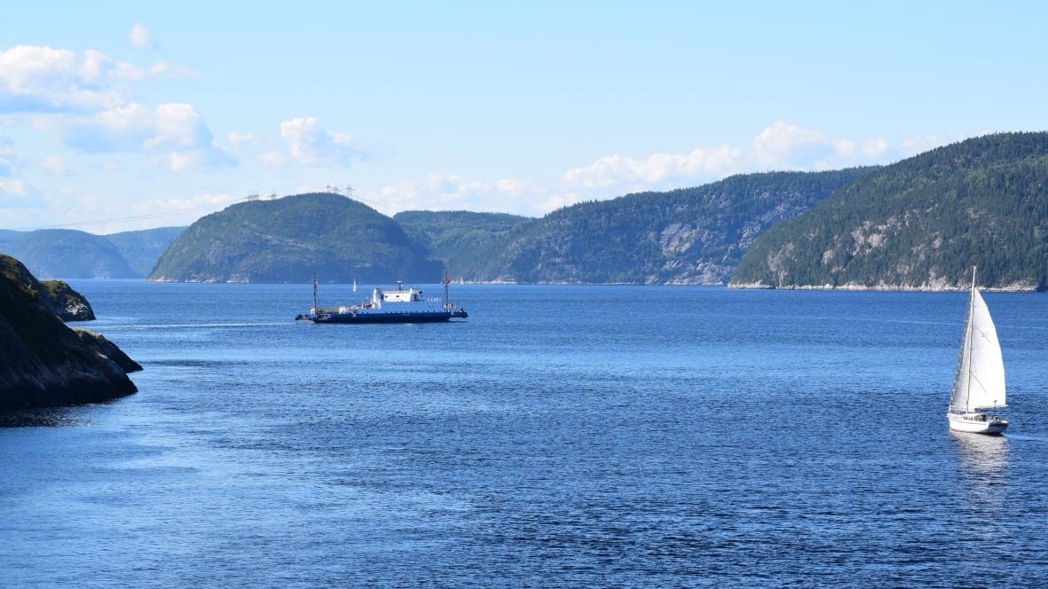 saguenay-fjord-1 Beauty shot of mountains, blue water, a sailboat and a ferry.