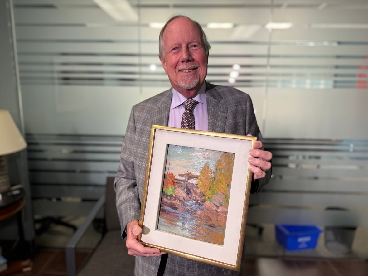 steven-bookman A person holds a gold-framed painting in his hands.