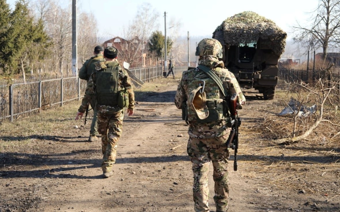 ukraine-crisis-kursk-1 Soldiers with rifles walk along a road.