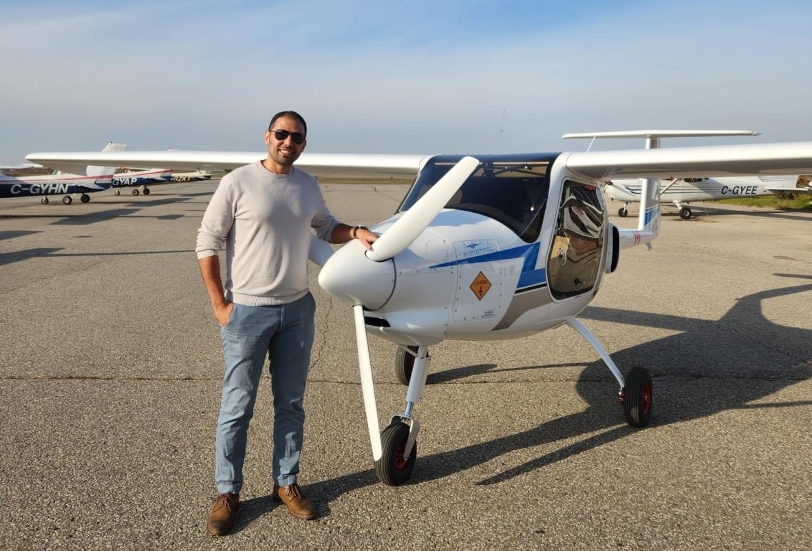 A man standing in front of a plane in an airfield.