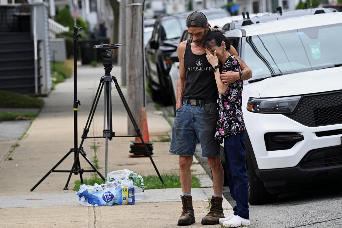 massachusetts-fire-1 A man and a woman bow their heads while standing on a sidewalk.