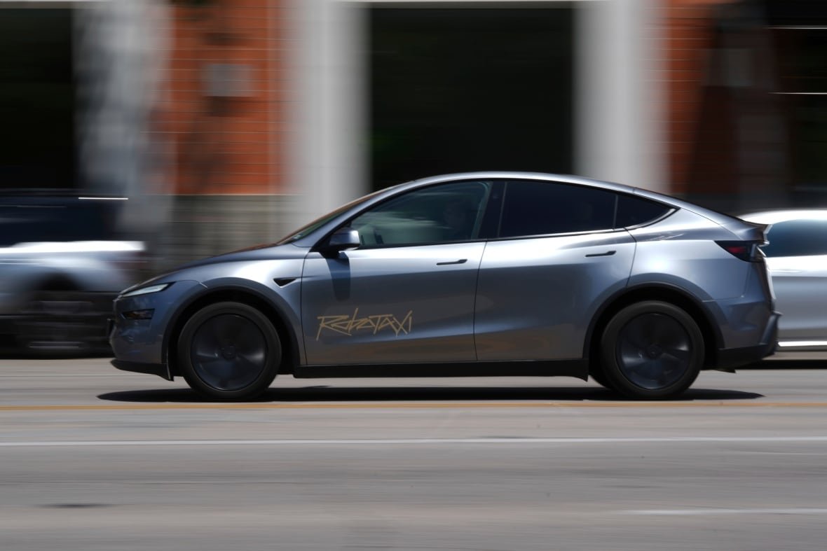 musk-self-driving-promises-1 A silver-coloured sedan with the word Robotaxi written on the driver-side door